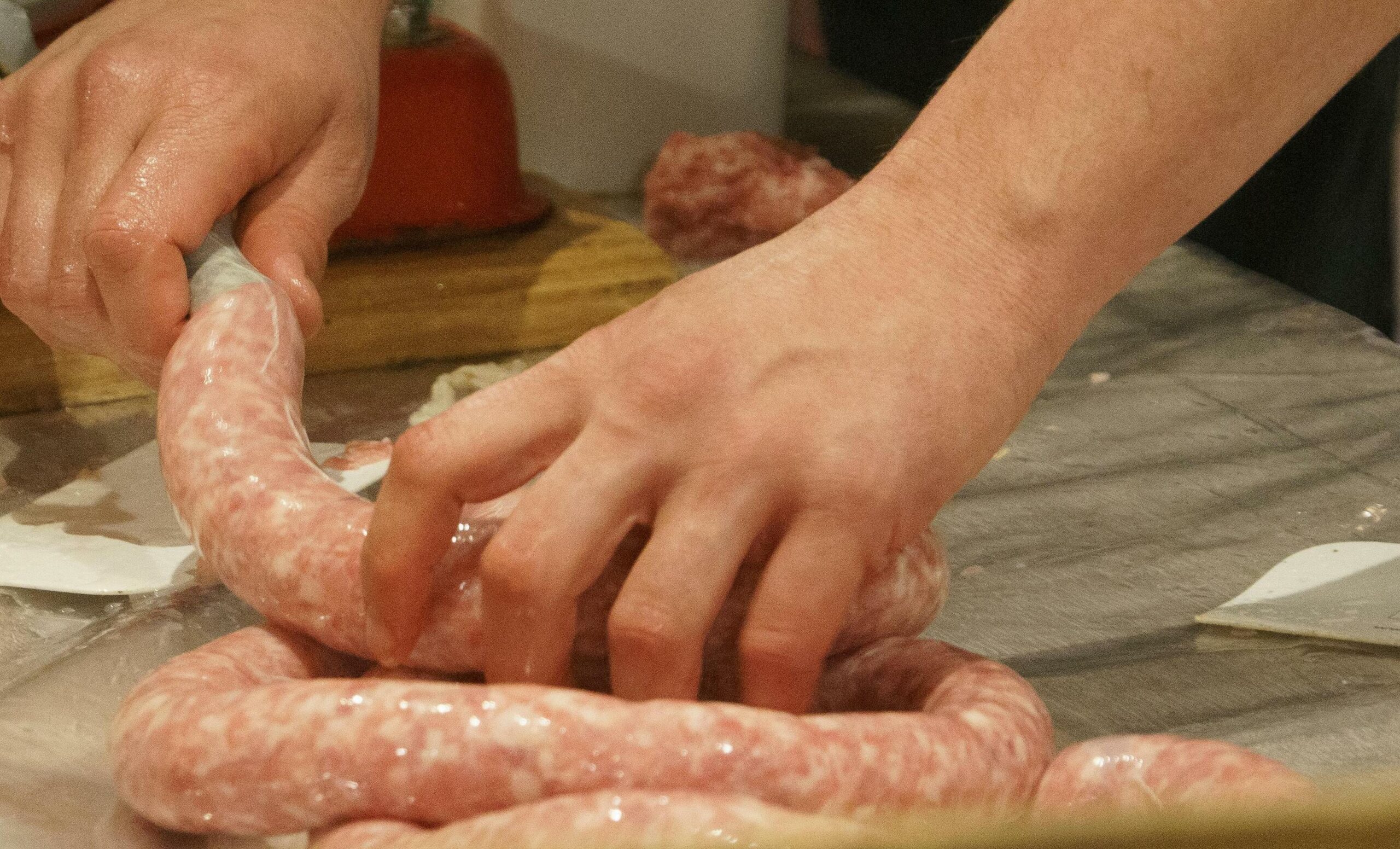 A captivating scene showing the traditional steps of how to make Vietnamese sausage, featuring an artisan carefully stuffing and tying the crimson links by hand