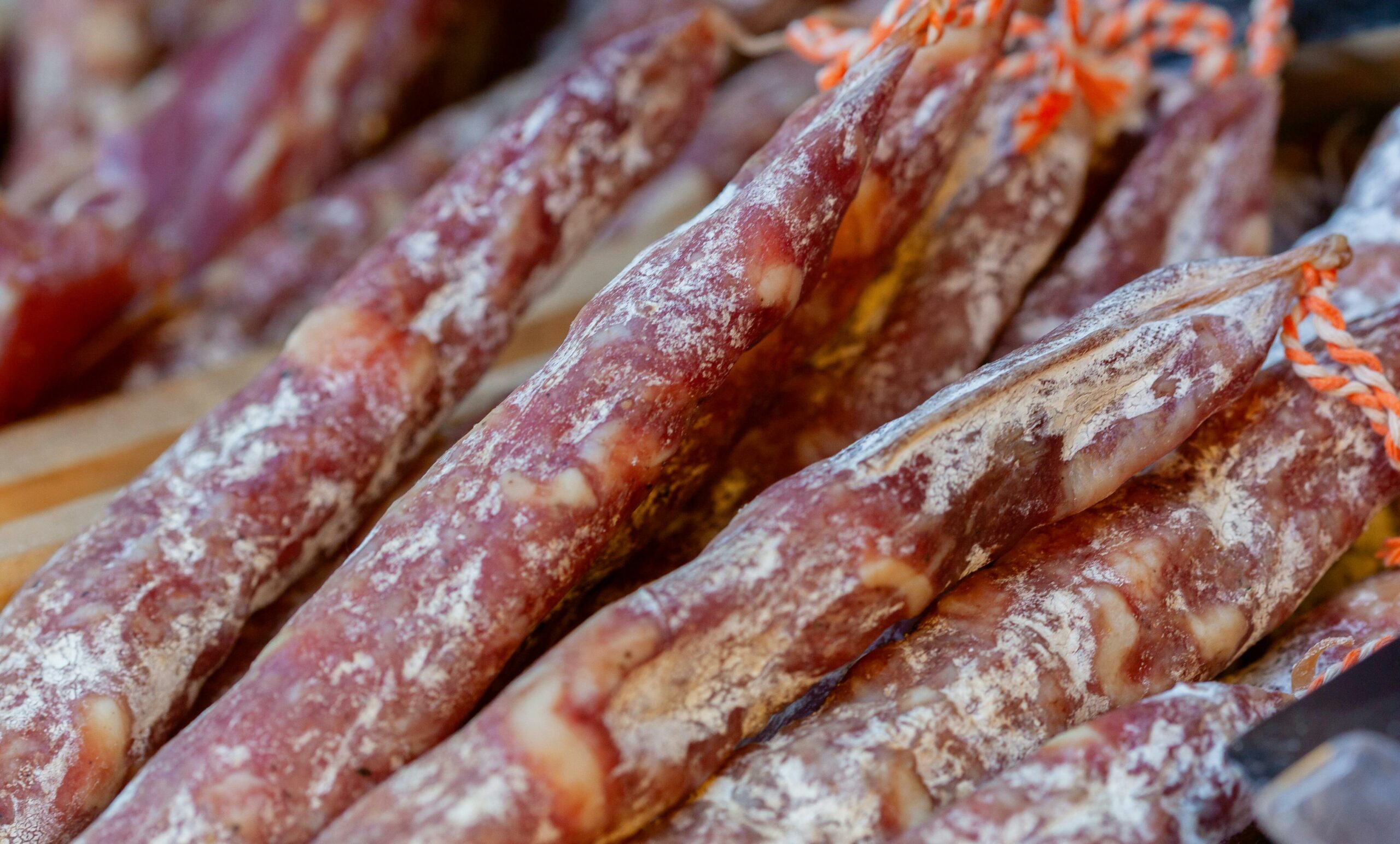 Traditional dried Vietnamese sausage (lap xuong) hanging in organized rows under the clear sky, illustrating the natural sun-curing method and the mastery of the elements