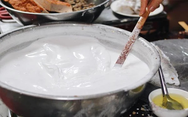 Cook preparing smooth rice batter for banh cuon Hanoi