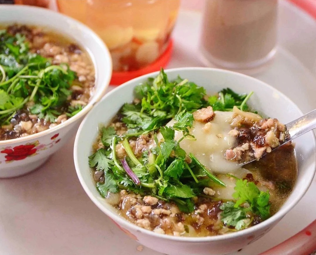 A steaming bowl of traditional bánh đúc nóng garnished with minced pork, wood-ear mushrooms, and fried shallots during Hanoi autumn.