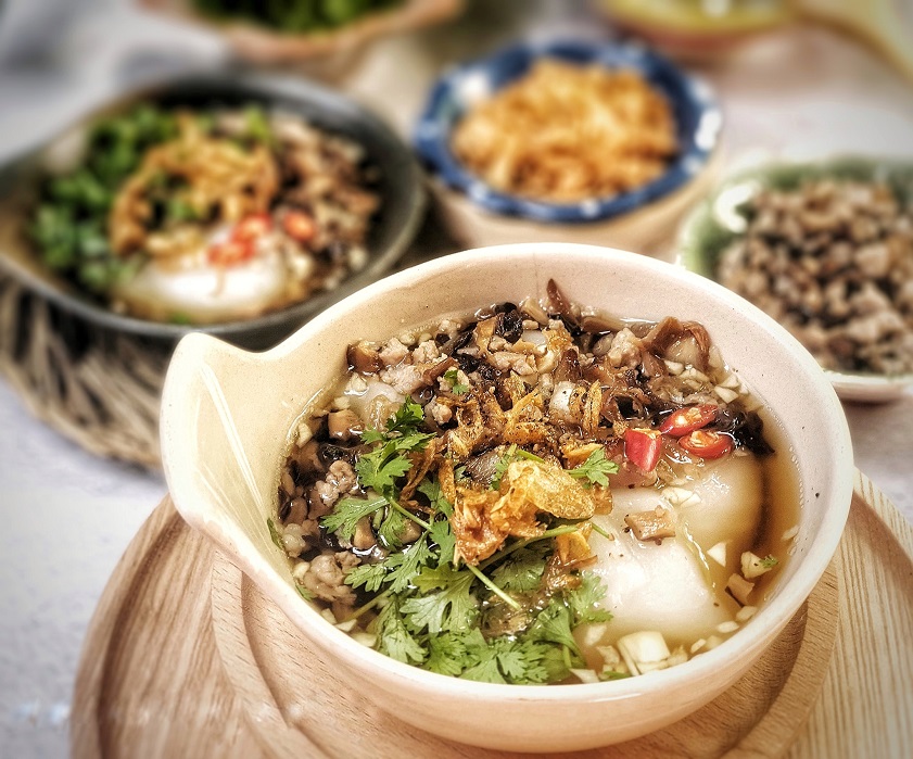 A traditional street food vendor serving hot bánh đúc nóng on a chilly autumn day in Hanoi.