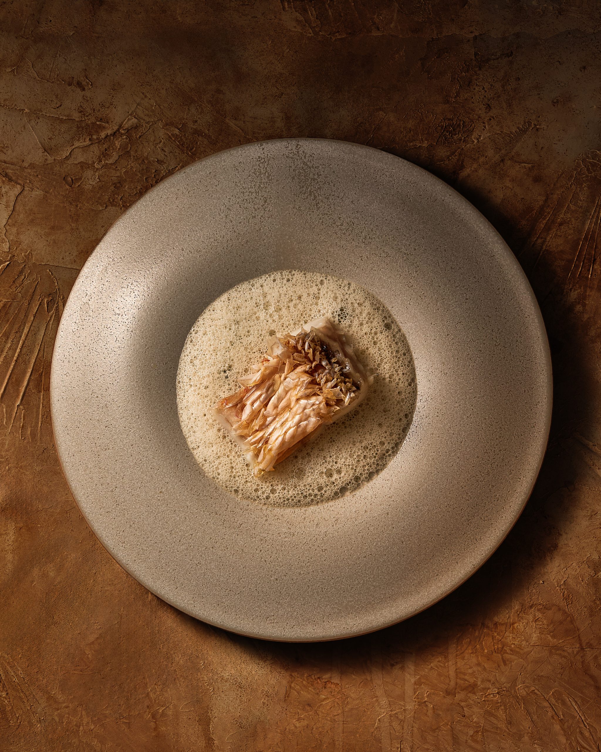 through a contemporary Vietnamese dining experience at Chapter.A member of Chapter’s service team presenting the seasonal fish course to a guest.