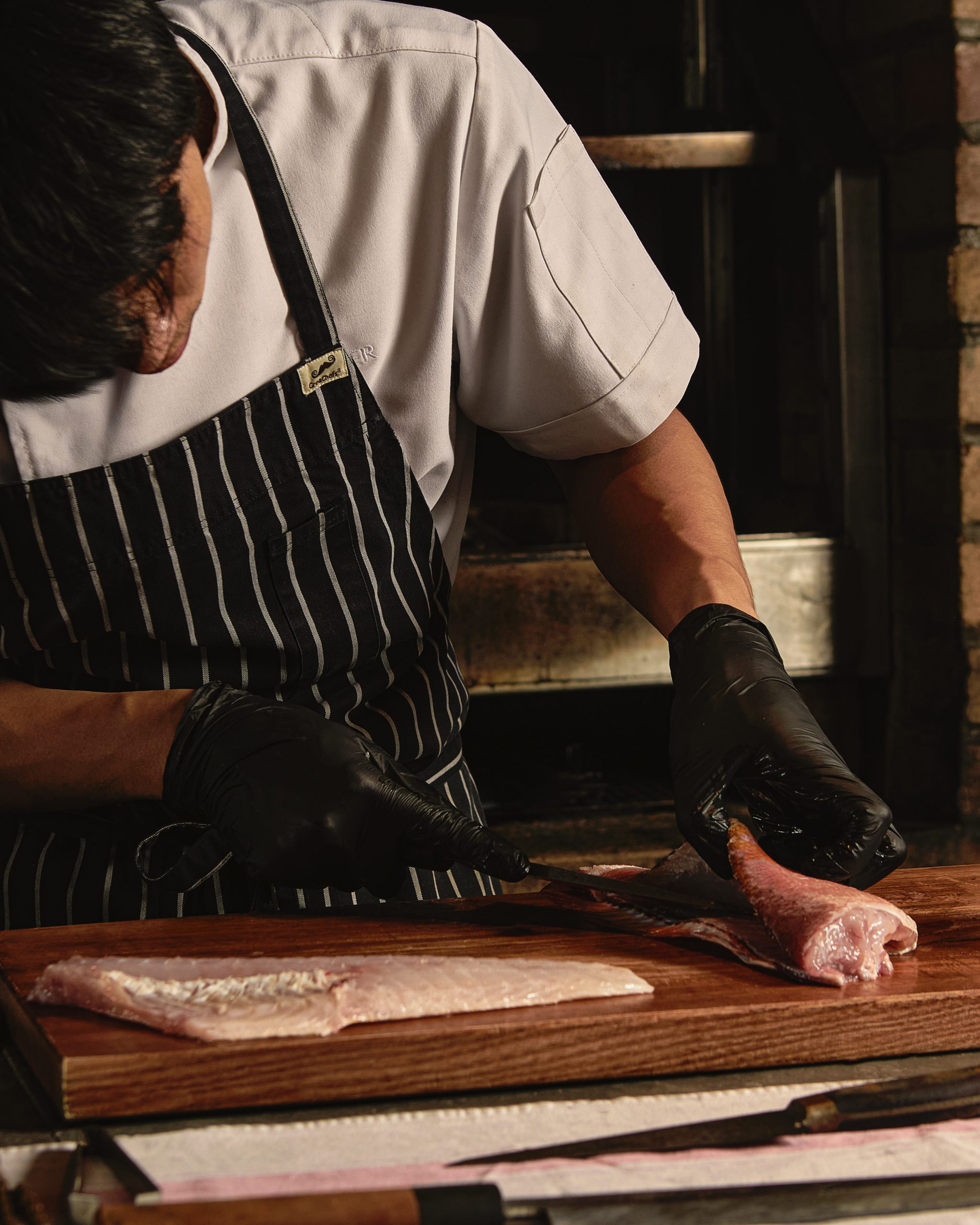 A chef inspecting fresh fish before preparation in Chapter’s kitchen.