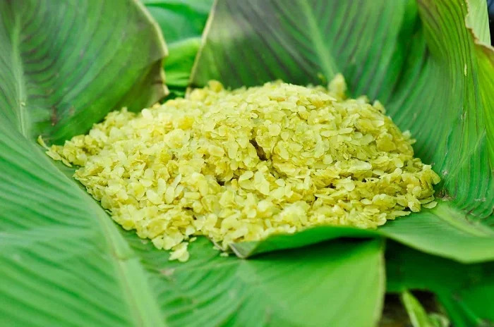 Young green rice flakes on a lotus leaf beside ripe bananas